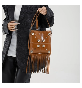 Detail view of brown vintage motorcycle bag featuring silver studs and long tassels