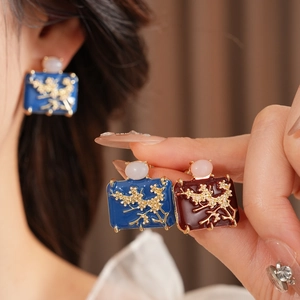 Detail of vintage enamel geometric earrings with gold floral patterns and pearl accents