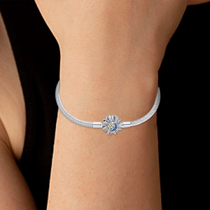 Close-up of silver snake chain bracelet featuring sun and moon charm with colored crystals
