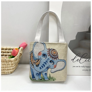 Detail of blue elephant embroidery on small canvas tote with silver-white handles