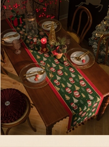 Detailed view of green jacquard table runner with Santa and tree patterns for Christmas