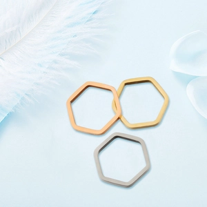 Gepolijste zeshoekige hangers in goud, roosgoud en zilver op een blauwe basis