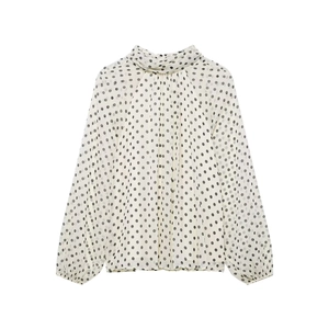 Dettaglio camicia bianca a pois neri con collo alto e polsini a lanterna eleganti