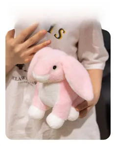Detailed view of soft pink and white plush rabbit with long floppy ears held by a person