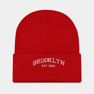 Detailed close-up of white Brooklyn embroidery on a red ribbed knit beanie cap