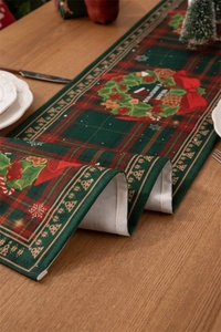 Detailed texture of red and green plaid table runner with Merry Christmas wreath print