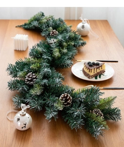 Close-up of dense Christmas pine garland with natural pinecones on a rustic wooden table