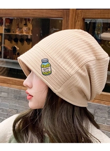 Detailed view of Happy Pills medicine bottle enamel pin on a beige knitted beanie
