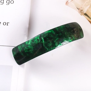 Detail view of a long dark green marble acetate hair clip with a smooth glossy finish