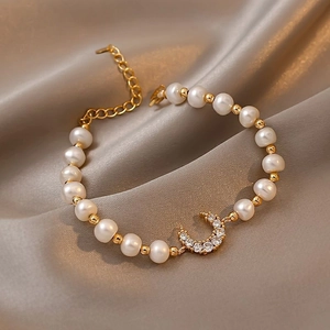 Macro detail of freshwater pearl bracelet with gold crescent moon charm and crystals