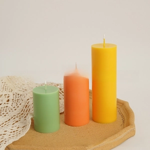 Detailed view of three colorful pillar candles in green orange and yellow on a ceramic tray