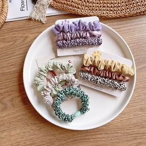Flat lay of leopard print and solid fabric hair scrunchies on a wooden background