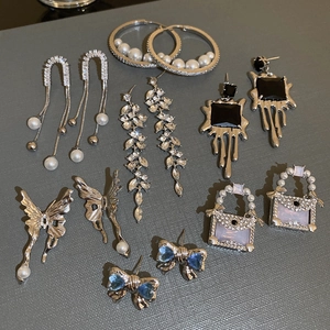 Detailed flat lay of silver bow and pearl earrings set with rhinestone tassels