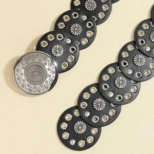 Close-up of black leather belt with silver circular buckles and flower rivets for Y2K style