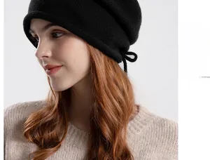 Close-up of black knit beanie with drawstring detail and rolled edge design on model