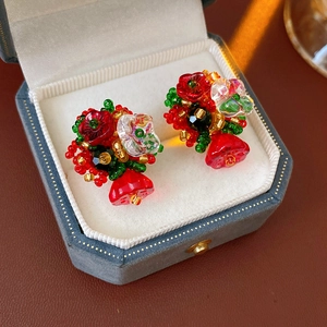 Detailed shot of vintage beaded flower earrings in red and green inside a grey velvet box