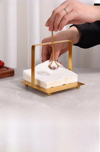 Detail of golden metal tissue holder with crystal weighted arm on marble table