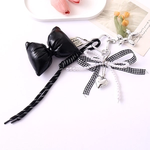 Detail of a pearl keychain with a black bow ribbon and silver heart dog charms