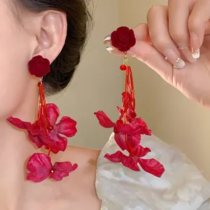Détail de boucles d'oreilles rose floquée rouge avec longs glands de perles