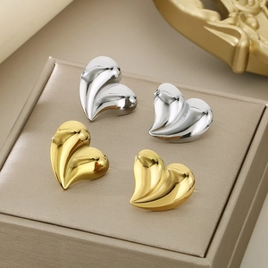 Detailed view of irregular heart earrings in polished 18K gold and silver finishes