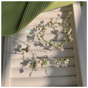 Close-up of lily of the valley jewelry set with green enamel leaves and pearls