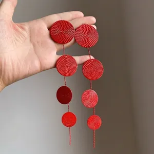 Détail de longues boucles d'oreilles rouges avec disques texturés et style ethnique rétro