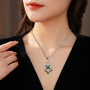 Détail du collier avec pendentif émeraude, motif papillon et cristaux scintillants