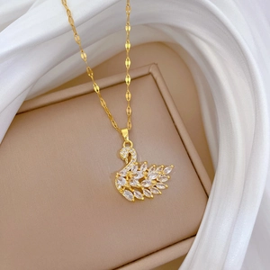 Titanium steel swan necklace with white crystals on a gold chain over silk fabric