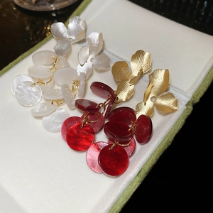 Detail of floral tassel earrings with metallic petals and colorful layered acrylic discs