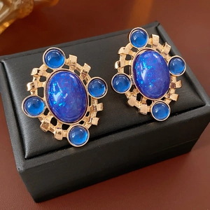 Close-up of vintage gold earrings with large blue stones on a premium jewelry box