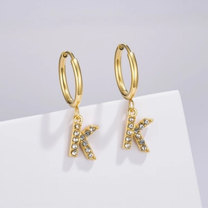 Detail of gold huggie hoop earring with K letter pendant inlaid with clear crystals