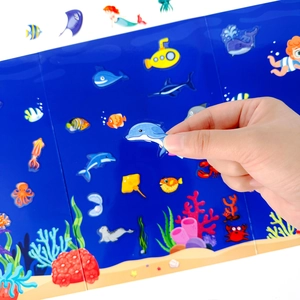 Close-up of child's hand applying a dolphin sticker on an ocean-themed scene book