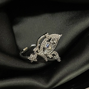 Macro shot of silver butterfly ring with cubic zirconia stones on black silk fabric