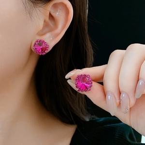 Close-up of pink crystal stud earrings with a sparkling diamond halo worn by a model