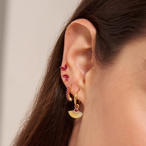 Close-up of gold fan earrings with marquise red zircons and sparkling gemstone studs