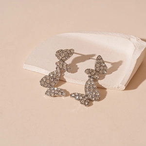 Sparkling silver butterfly tassel earrings with zircon stones on stone display