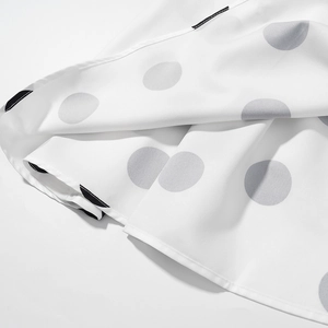 Détail en gros plan du tissu en mousseline blanche avec motifs à pois gris et noirs