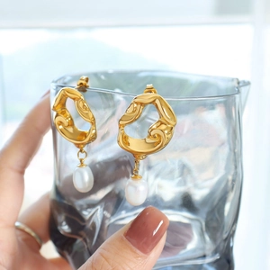 Détail de boucles d'oreilles irrégulières en or 18k avec perles d'eau douce blanches