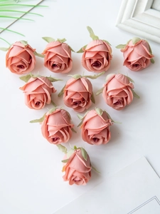 Top view of ten soft pink artificial silk roses arranged on a clean white surface