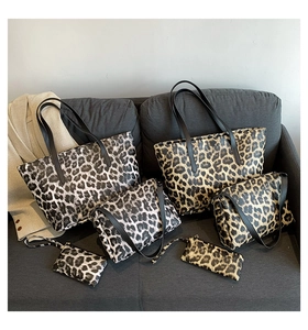 Leopard print 3-piece bag set with tote, crossbody bag, and clutch on a sofa