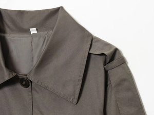 Detail shot of the stand-up collar and shoulder straps of this twill trench coat with buttons