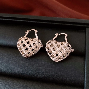 Macro shot of rose gold heart-shaped earrings with intricate hollow woven texture