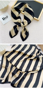Detail of black and gold striped silk scarf with coco puss lettering and elegant texture