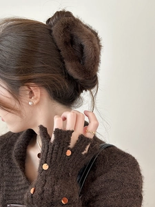 Détail d'une grande pince à cheveux en fourrure marron foncé pour un chignon chic