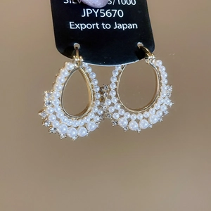 Detail of gold hoop earrings featuring double rows of faux pearls and fine rhinestones