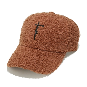 Dettaglio del cappellino in pile caramello con ricamo a croce 'faith' in filo nero