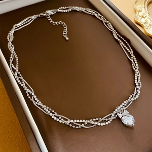 Detail of three-layer silver heart necklace with zircon stones in a jewelry box