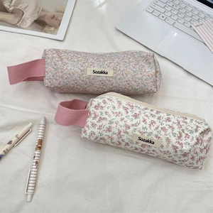 Detailed close-up of floral pencil cases with pink handles and woven brand label