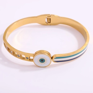 Detailed view of gold evil eye bangle with blue enamel stripes and cubic zirconia accents