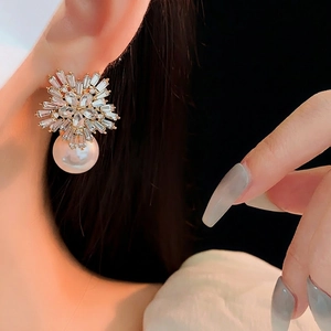 Elegant snowflake zirconia earrings with large white pearls and gold base on a female model